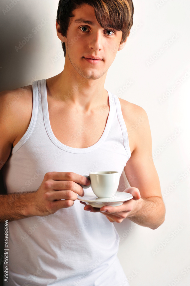 Closeup of young, handsome man thinking. Standing against wall a Closeup of young, handsome man thinking. Standing against wall a