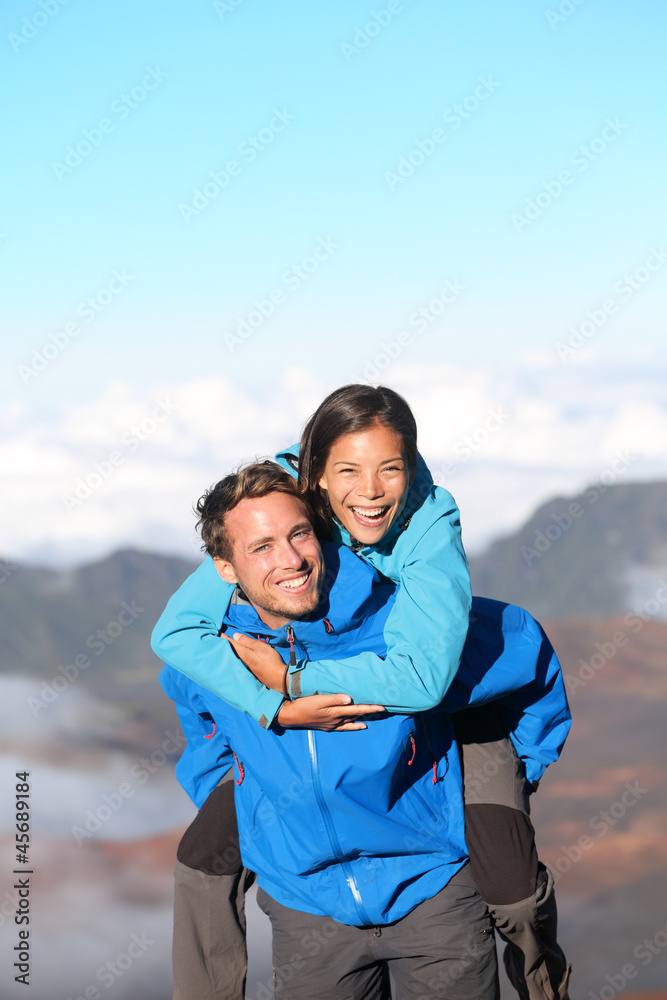 Hiking couple piggybacking happy