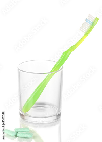 Toothbrush in glass and chewing gum isolated on white