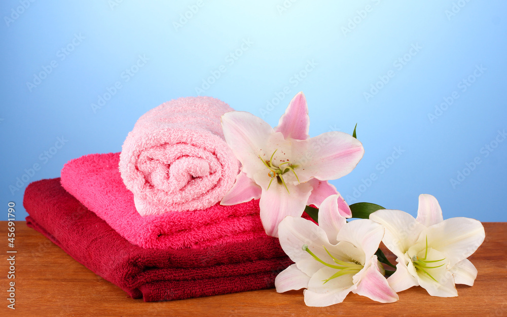 stack of towels with pink lily on blue background. stack of towels with pink lily on blue background.