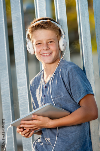 Cute teen boy holding tablet outdoors. Free Download Cute teen boy holding tablet outdoors. - GFXLoad