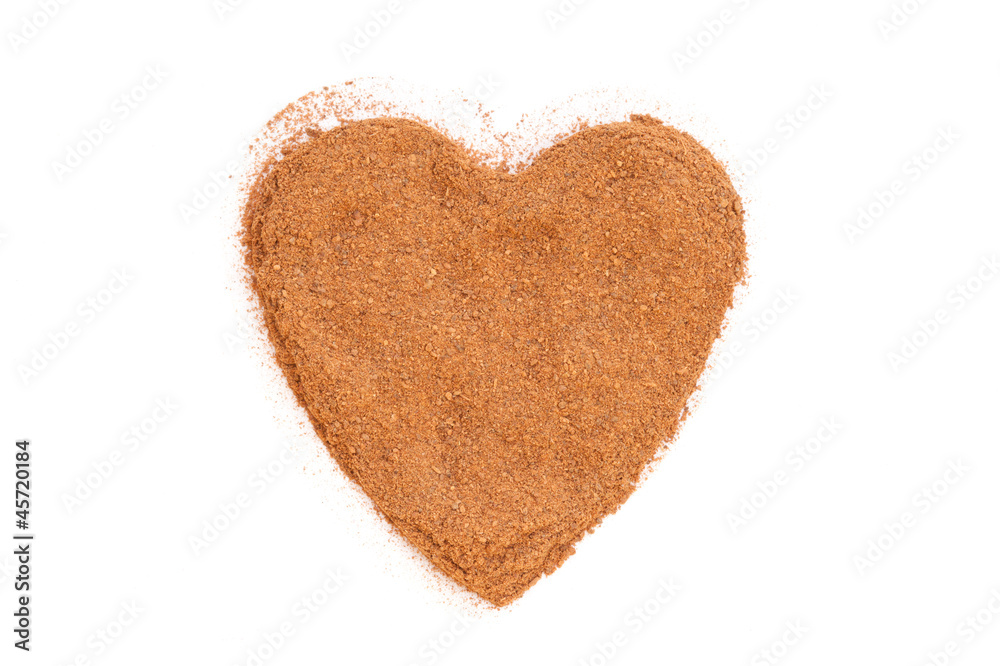 Heap of ground Cinnamon isolated in heart shape on white backgro