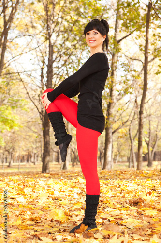 Pretty woman doing sport exercises in the autumn park