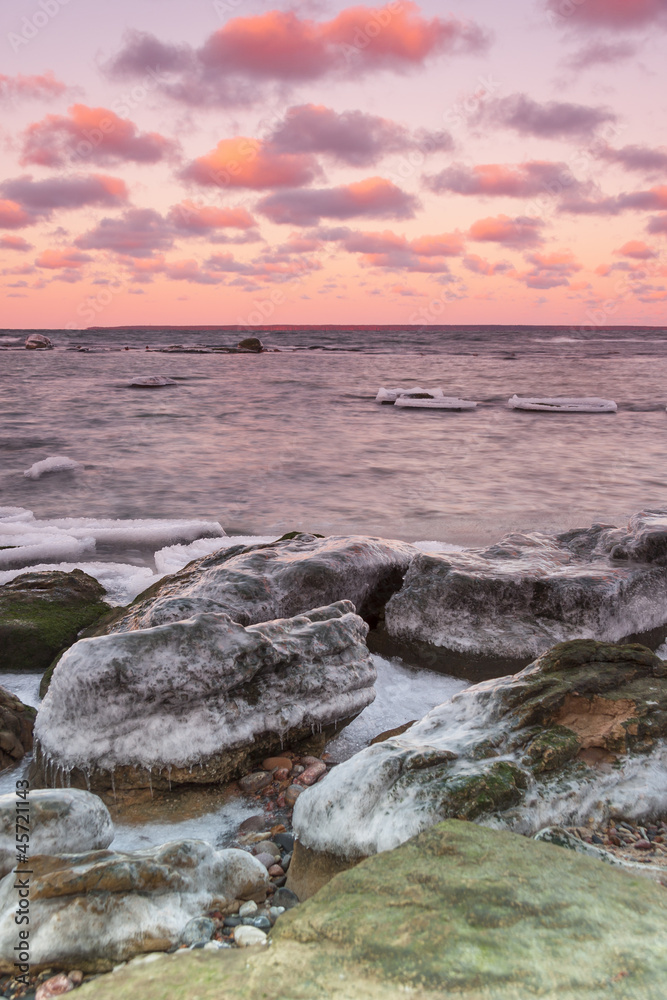 Icy stones near sea coast at sunset