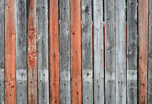 Old wooden fence with gray and orange mixed planking