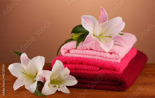 stack of towels with pink lily on a brown background