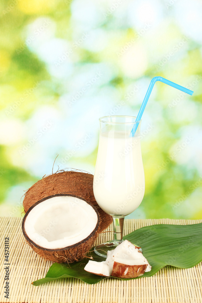 glass of coconut milk and coconuts on green background close-up glass of coconut milk and coconuts on green background close-up