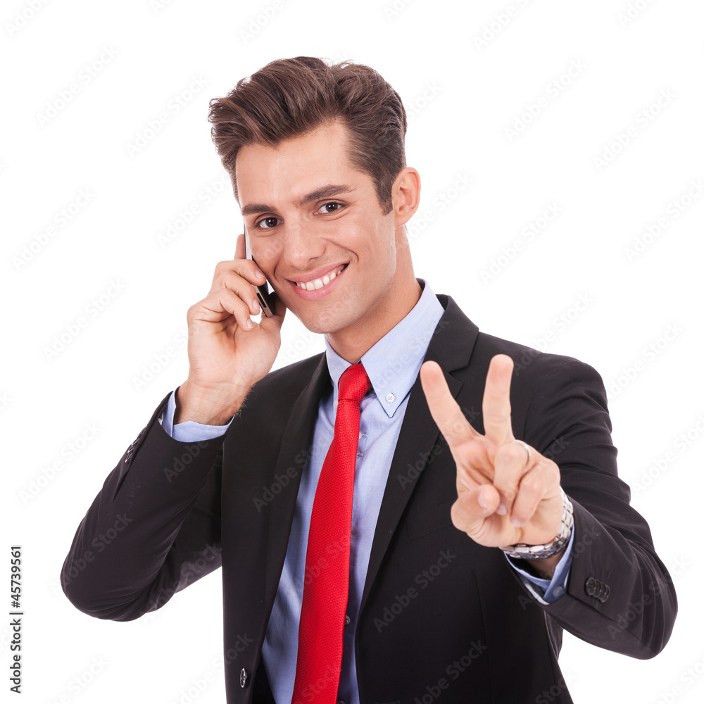 business man making victory sign while talking on phone business man making victory sign while talking on phone