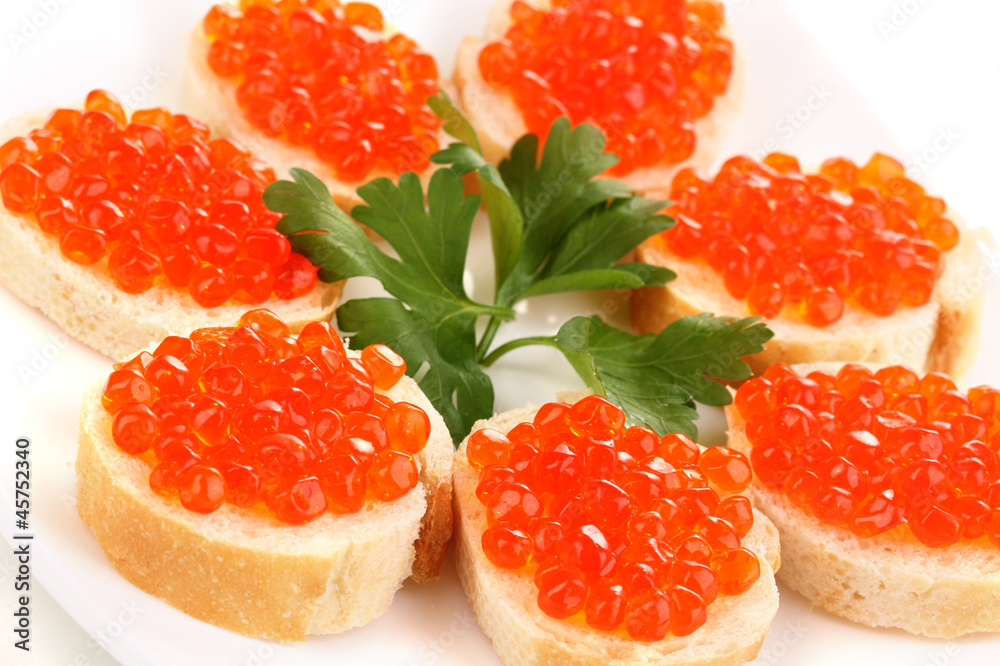 Red caviar on bread on white plate close-up