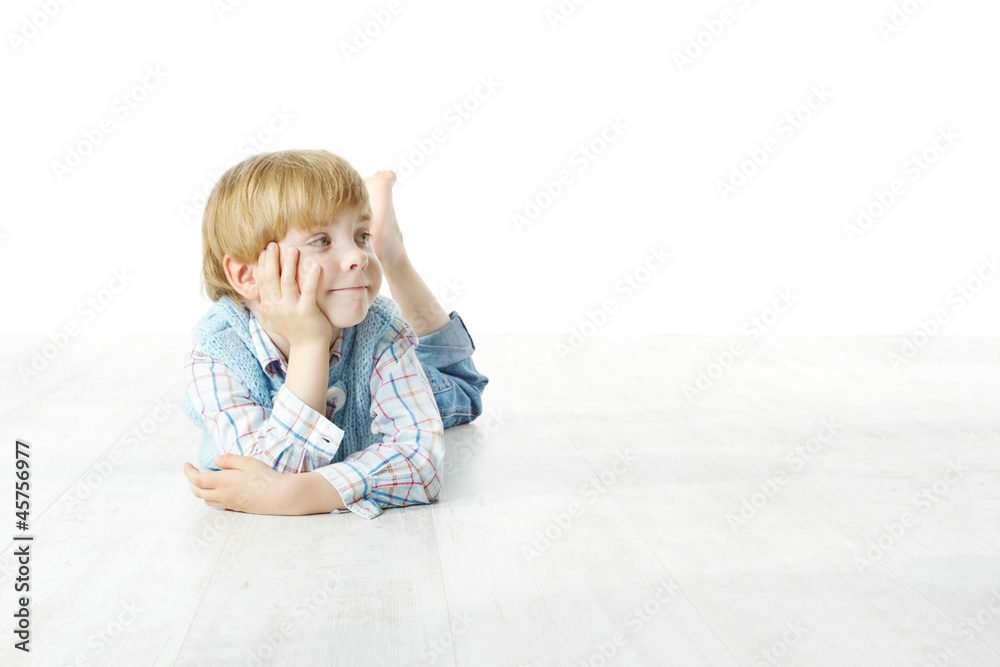 Little boy lying down on floor and looking up to the side Little boy lying down on floor and looking up to the side