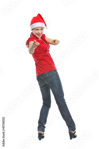 Smiling young woman in Santa hat pointing in camera