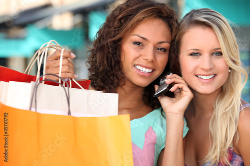 two young women after shopping, one is calling someone