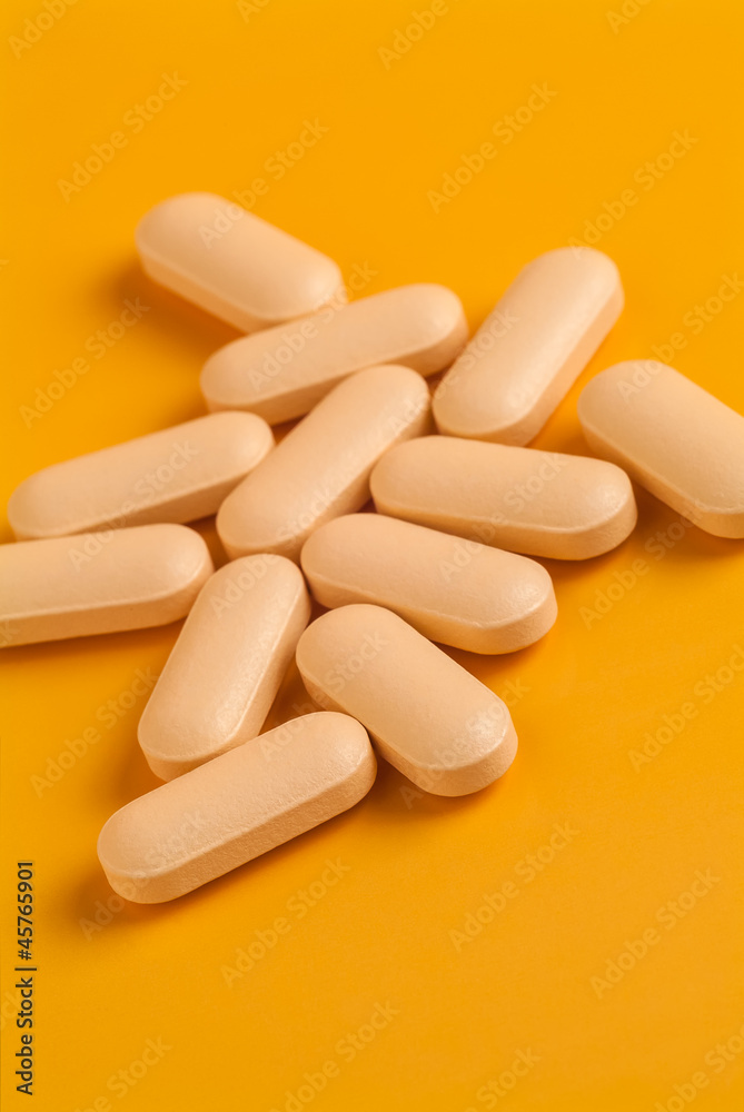 Orange vitamin pills on an orange background Orange vitamin pills on an orange background