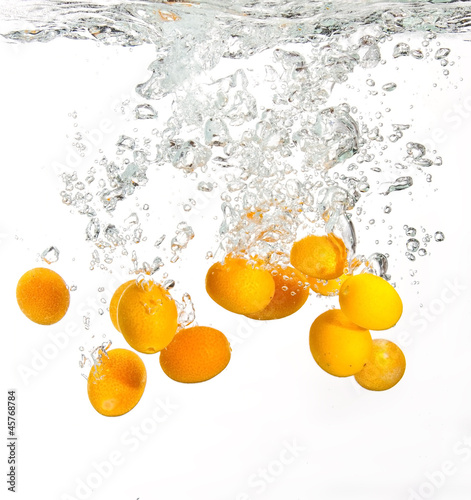Fototapeta Naklejka Na Ścianę i Meble -  Yellow oranges falling into water