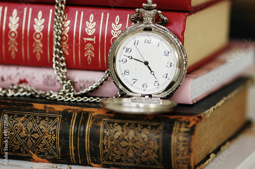 Old vintage pocket-watch and books like Alice in Wonderland