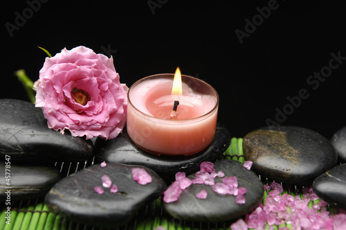 Spa sitting with rose and herbal salt with candle on pebbles