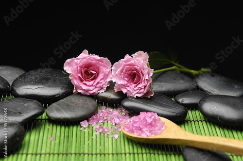 herbal salt in spoon with rose stones on green mat