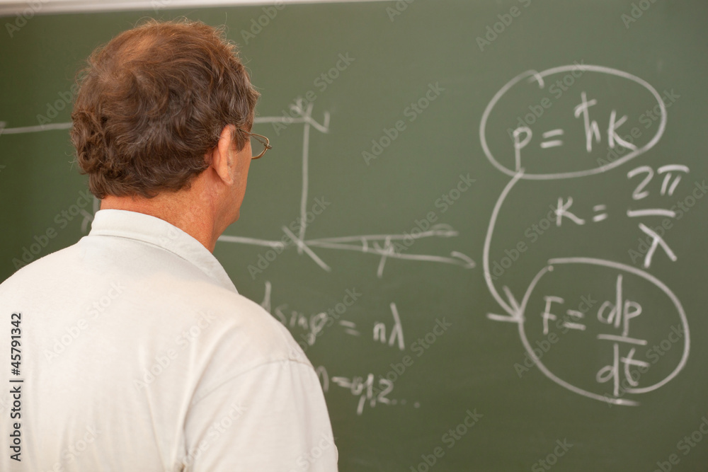 Scientist looking at formula on blackboard, back