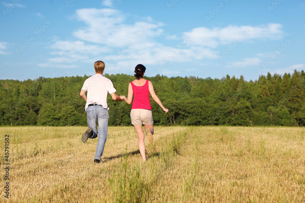 Husband and wife running in field