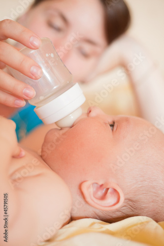 Mom feed baby with bottle in bed