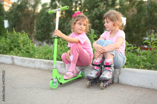 Two little girls with roller, scooter seat on border
