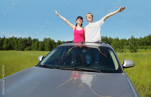 Husband, wife pose in hatch of car before hood in field
