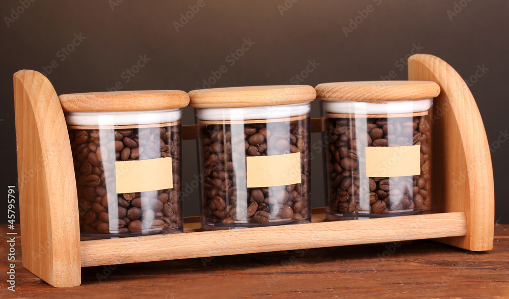 Coffee beans in jars on table on brown background