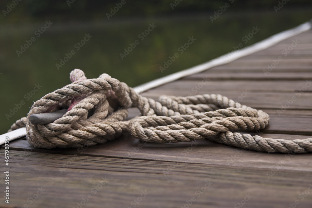 A thick rope tied into a sailor's knot by the harbor