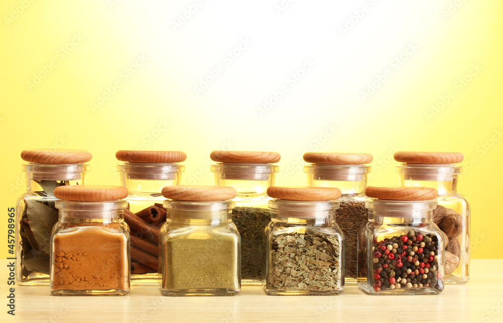 powder spices in glass jars on yellow bavkground powder spices in glass jars on yellow bavkground