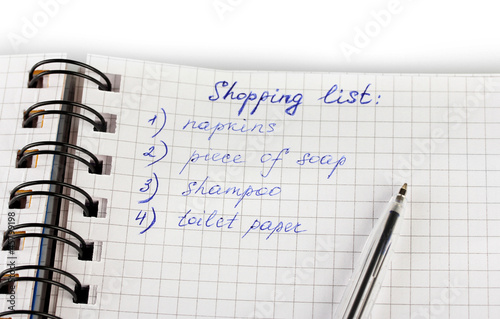 shopping list in a notebook on white background close-up