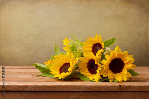 Sunflowers on wooden table against grunge background