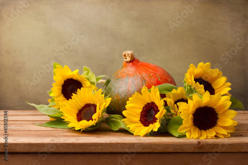 Fototapeta Naklejka Na Ścianę i Meble -  Sunflowers and pumpkin on wooden table against grunge background