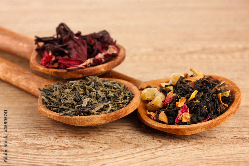 assortment of dry tea in spoons, on wooden background assortment of dry tea in spoons, on wooden background