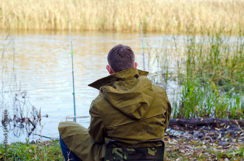 The fisherman sits on a stool a back