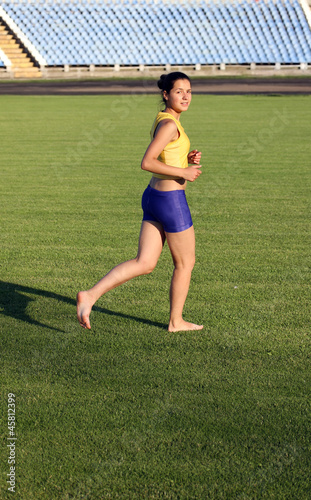 Beautiful teenage sport girl running on the grass.