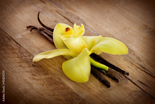 Fototapeta Naklejka Na Ścianę i Meble -  Vanilla Pods And Flower on a Wooden Background