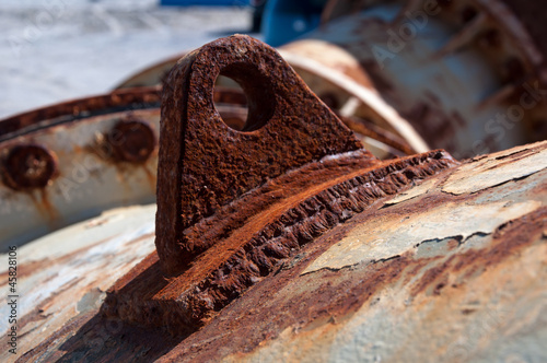 Rusted attachment welded to a large corroded steel pipe