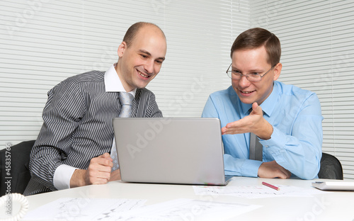 Two business men working on a laptop