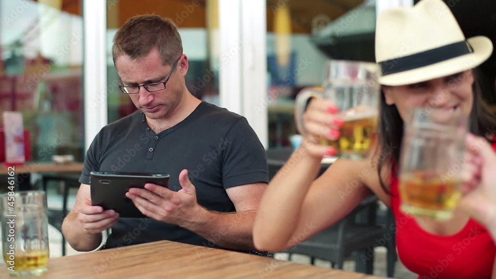 Young friends with tablet computer and beer in cafe, steadicam Young friends with tablet computer and beer in cafe, steadicam