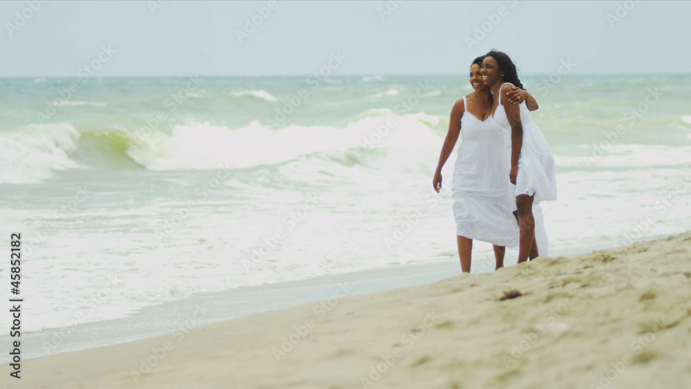 Diverse parent and daughter gossiping and walking by ocean Diverse parent and daughter gossiping and walking by ocean