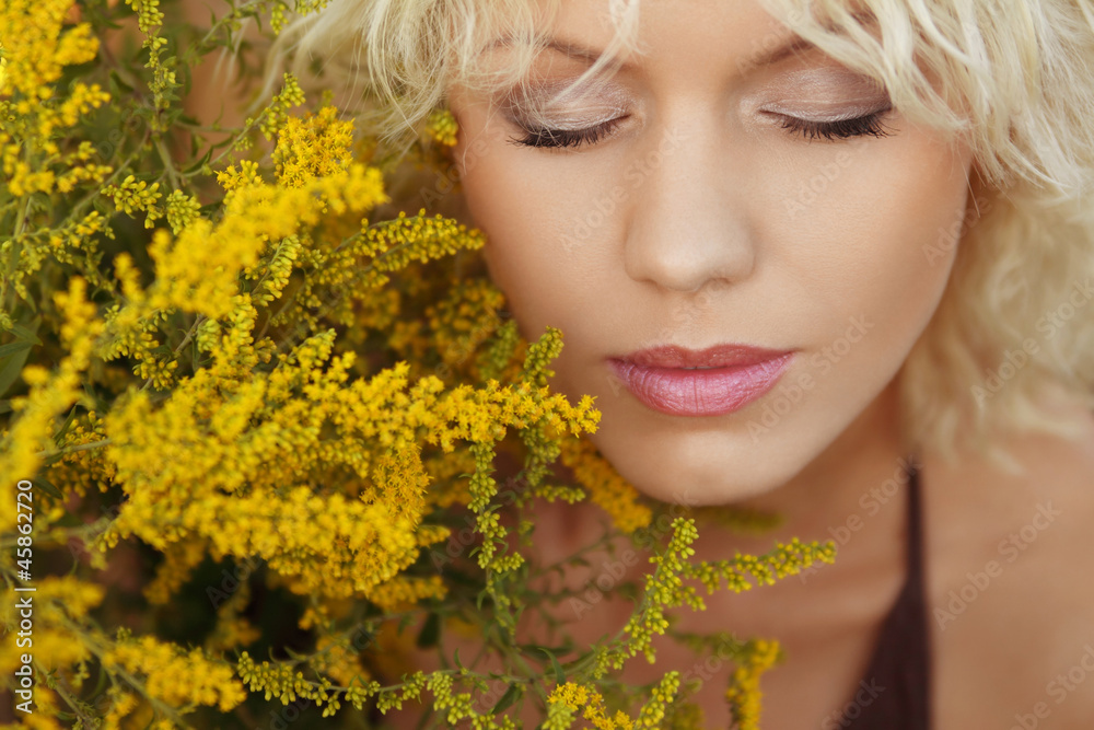 Beautiful young woman with closed eyes and yellow flowers