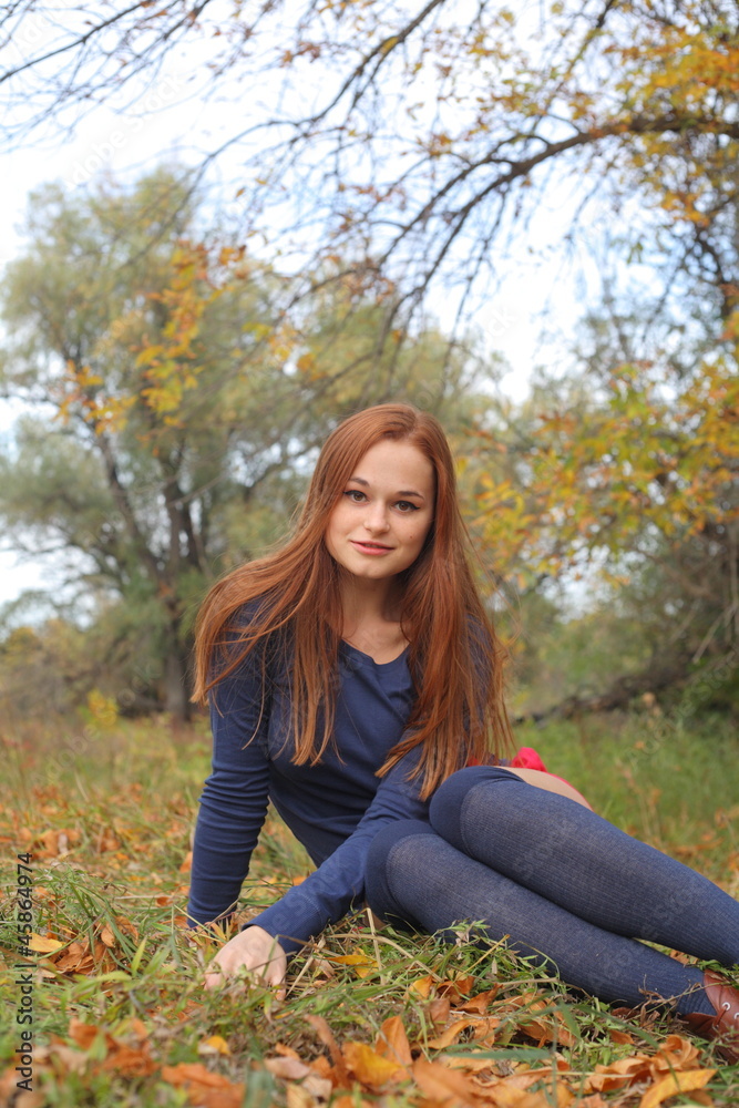 Portrait of a beautiful red-haired woman sitting on the grass Portrait of a beautiful red-haired woman sitting on the grass