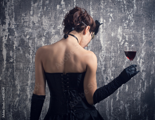 young woman in carnival mask and a glass of red wine.