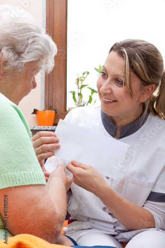 Pflegerin überreicht Patientin einen umschlag