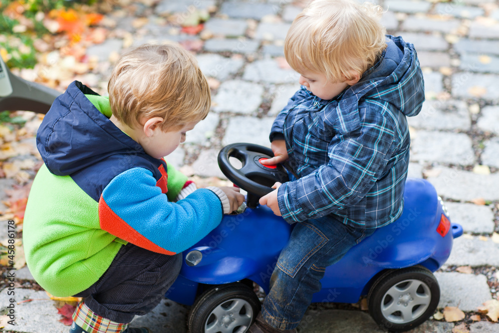 Two toddler boys playing with car in park Two toddler boys playing with car in park
