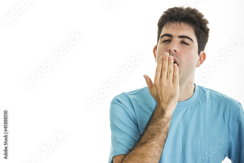 Yawning young man with blue shirt isolated on white background