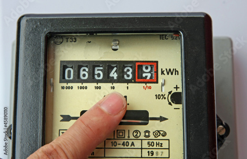 finger indicating the figures in an electric energy meter photo