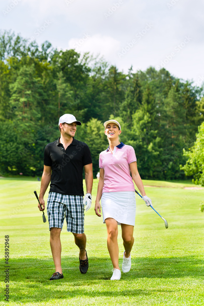 Junges sportliches Paar beim Golfen am Golfplatz Junges sportliches Paar beim Golfen am Golfplatz