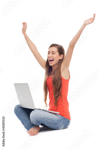 Woman sitting with laptop, arms raised © pikselstock