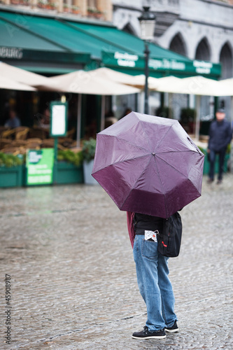 Tourist steht mit Regenschirm in der Stadt